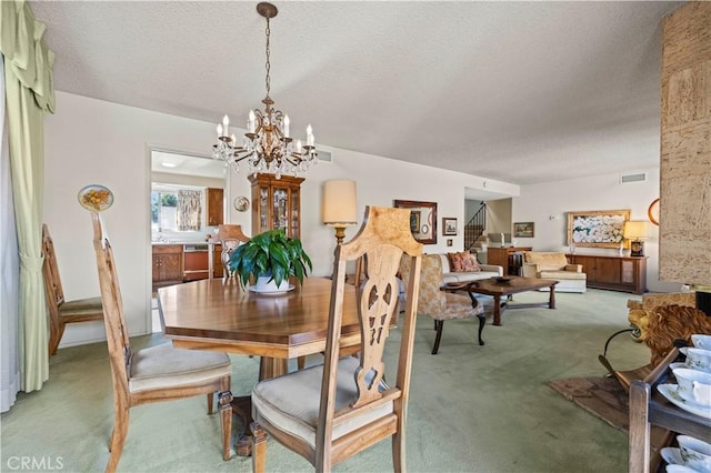 dining room featuring a chandelier, carpet, and a textured ceiling