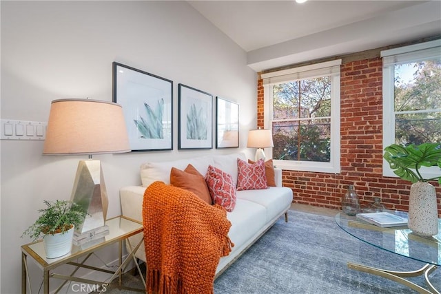 living room with lofted ceiling and brick wall