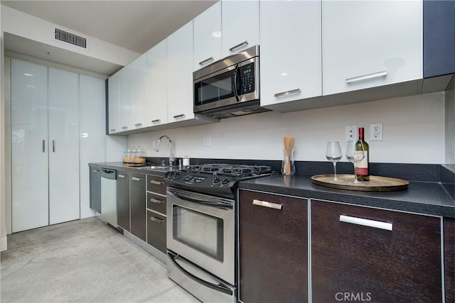 kitchen featuring appliances with stainless steel finishes, dark brown cabinets, white cabinets, and sink