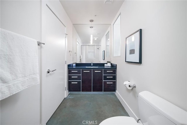 bathroom featuring toilet, vanity, a shower with shower door, and concrete flooring