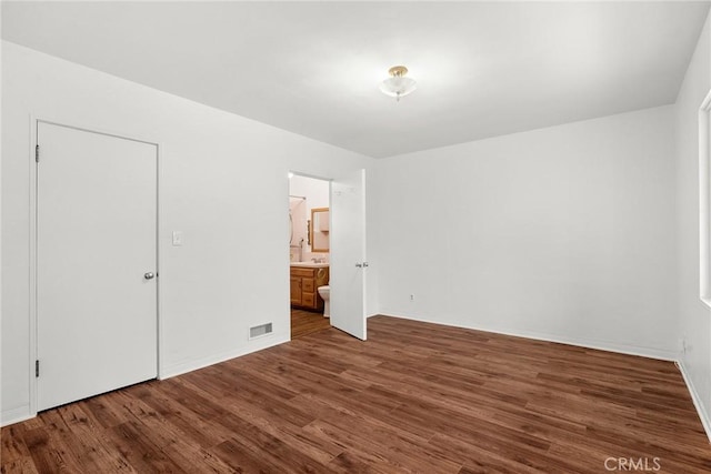 unfurnished bedroom featuring dark hardwood / wood-style flooring, sink, and ensuite bath