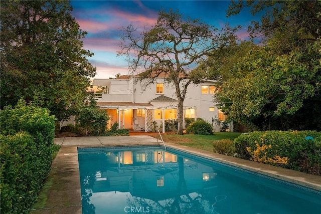 pool at dusk with a patio area