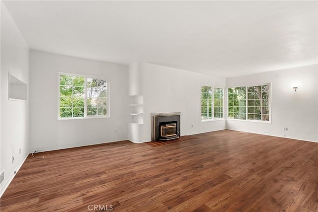 unfurnished living room with dark hardwood / wood-style floors and a healthy amount of sunlight