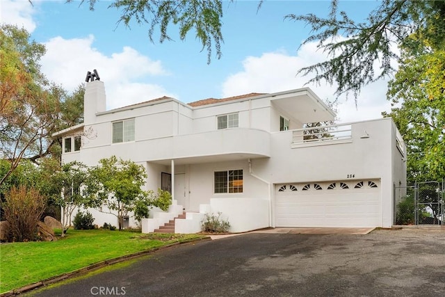 art deco house with a garage, a balcony, and a front yard