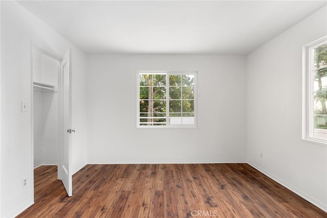 unfurnished bedroom featuring a spacious closet, dark wood-type flooring, and a closet