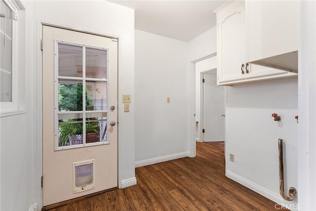 clothes washing area with dark wood-type flooring, cabinets, and heating unit