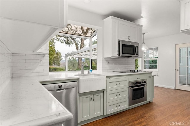 kitchen with sink, dark hardwood / wood-style flooring, decorative backsplash, stainless steel appliances, and light stone countertops