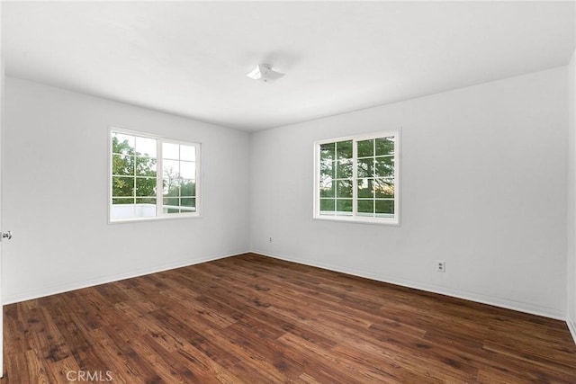 empty room featuring plenty of natural light and dark hardwood / wood-style floors