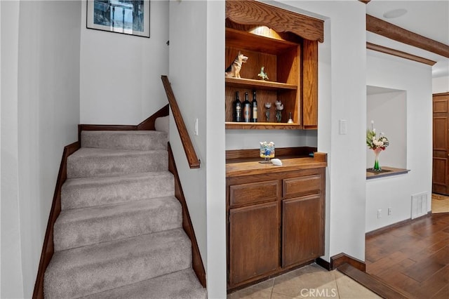 stairs featuring built in shelves, wood finished floors, visible vents, baseboards, and beamed ceiling