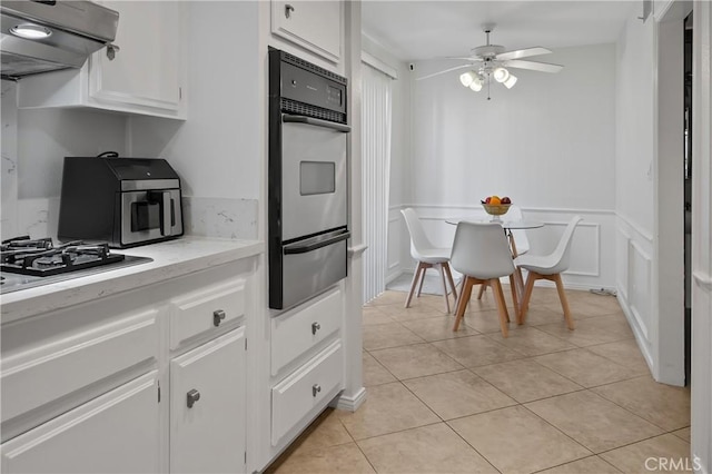 kitchen featuring ceiling fan, stainless steel appliances, light tile patterned flooring, range hood, and white cabinets