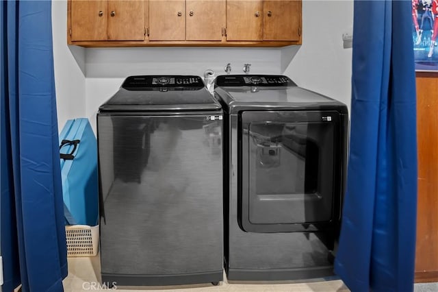 clothes washing area with cabinets and washing machine and clothes dryer