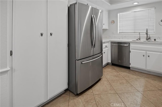 kitchen featuring light tile patterned floors, a sink, light countertops, white cabinets, and appliances with stainless steel finishes