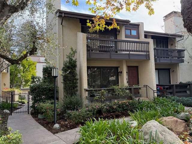 view of front of home with stucco siding, a chimney, and a gate