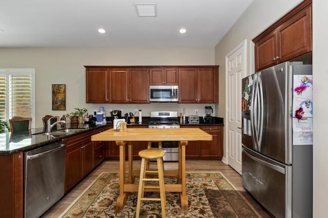 kitchen with wood counters, a kitchen bar, hardwood / wood-style floors, stainless steel appliances, and sink