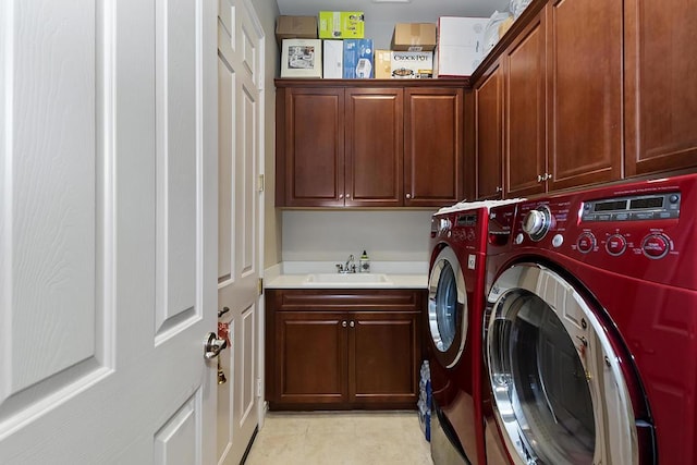 clothes washing area with cabinets, washing machine and clothes dryer, and sink