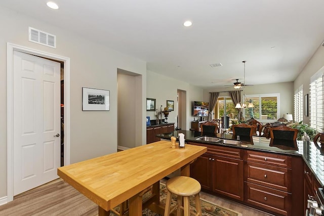 kitchen featuring ceiling fan, sink, kitchen peninsula, and light wood-type flooring