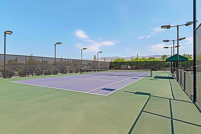 view of tennis court featuring a mountain view and basketball hoop