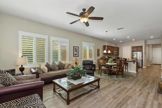 living room with ceiling fan and light wood-type flooring