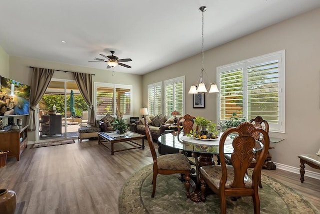 dining room featuring ceiling fan with notable chandelier and hardwood / wood-style flooring