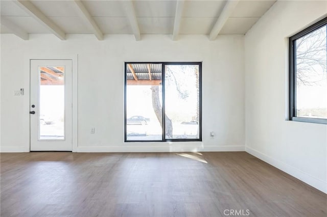 unfurnished room featuring a healthy amount of sunlight, beamed ceiling, and hardwood / wood-style flooring