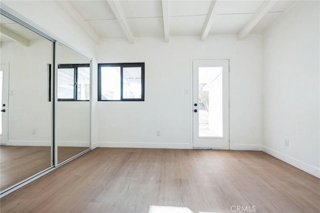 unfurnished room featuring light hardwood / wood-style floors and beam ceiling