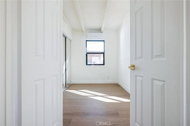 empty room with hardwood / wood-style floors, beamed ceiling, and a wall mounted air conditioner