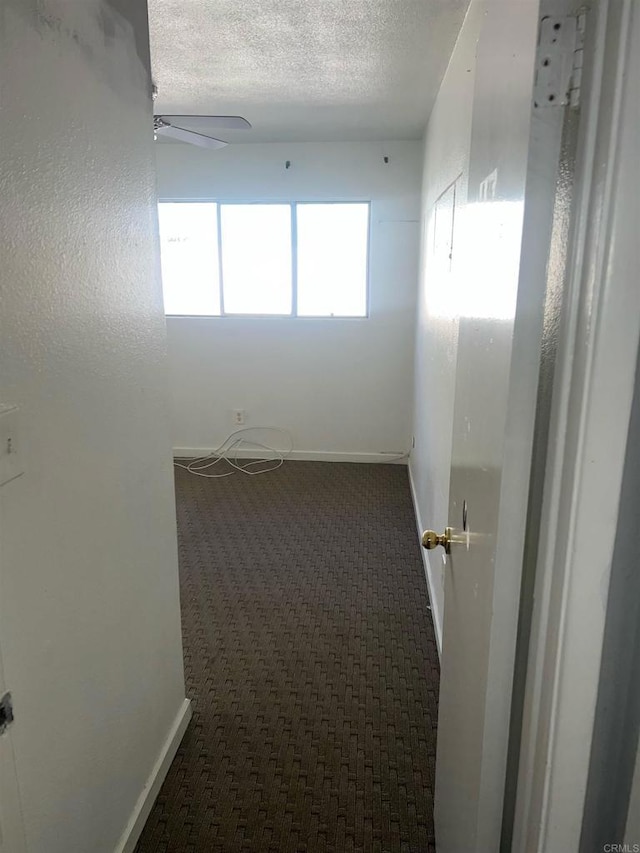 empty room featuring a textured ceiling, ceiling fan, and carpet flooring