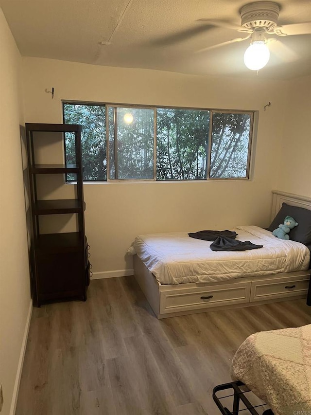 bedroom with ceiling fan, hardwood / wood-style floors, and multiple windows