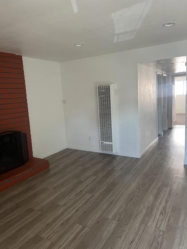 unfurnished living room featuring a large fireplace and dark hardwood / wood-style floors