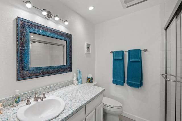 bathroom with a shower with door, vanity, and toilet