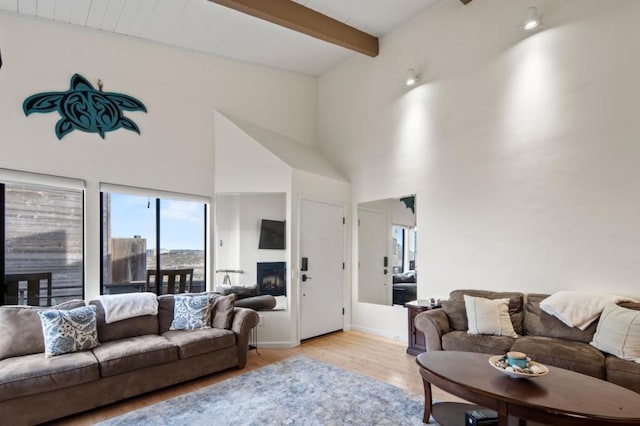 living room featuring beam ceiling, a high ceiling, and light wood-type flooring