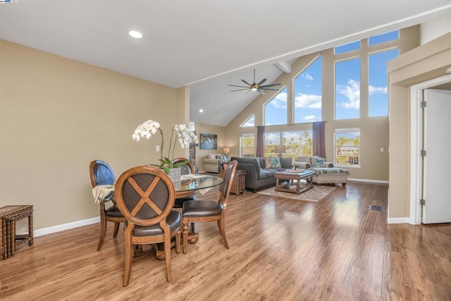 dining space with light hardwood / wood-style floors, ceiling fan, high vaulted ceiling, and beamed ceiling