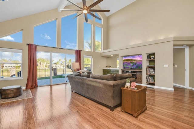 living room with light wood-type flooring, ceiling fan, beam ceiling, and high vaulted ceiling