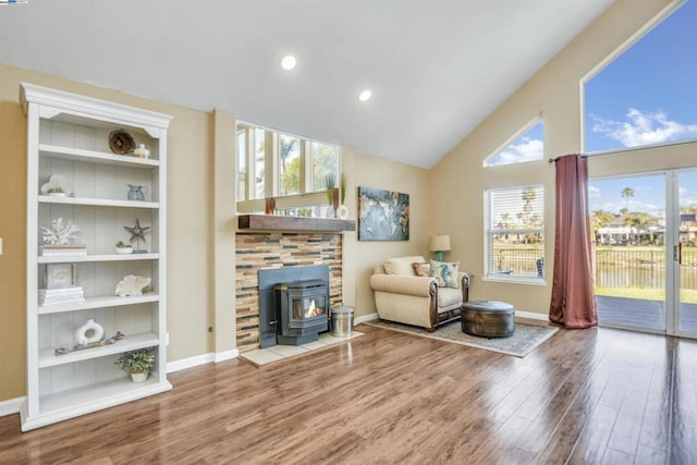 living room with built in features, a wood stove, and plenty of natural light