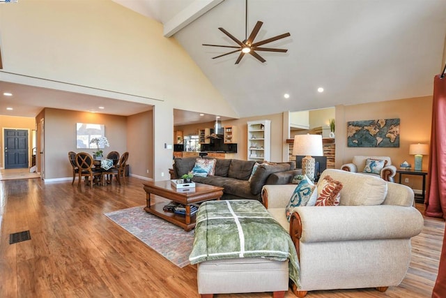 living room with high vaulted ceiling, ceiling fan, wood-type flooring, and beamed ceiling