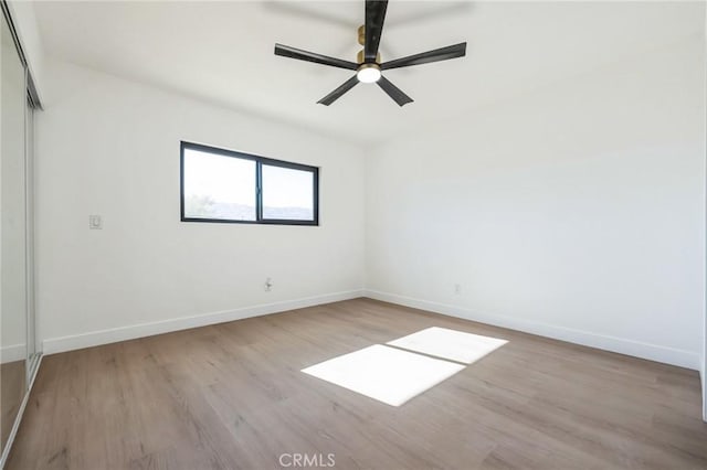 empty room with ceiling fan and light hardwood / wood-style flooring