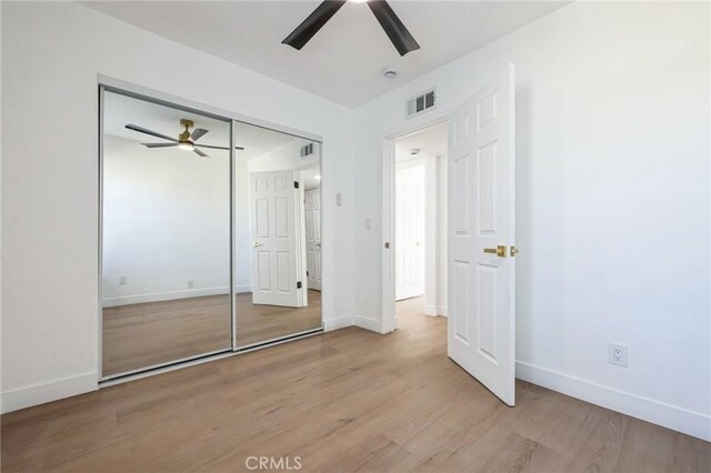 unfurnished bedroom featuring light hardwood / wood-style flooring, a closet, and ceiling fan