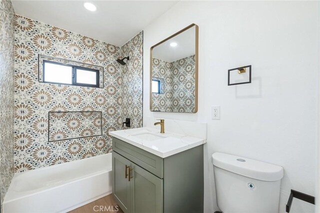 full bathroom featuring tiled shower / bath, vanity, and toilet