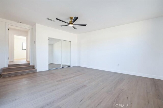 unfurnished bedroom with ceiling fan, a closet, and light hardwood / wood-style floors