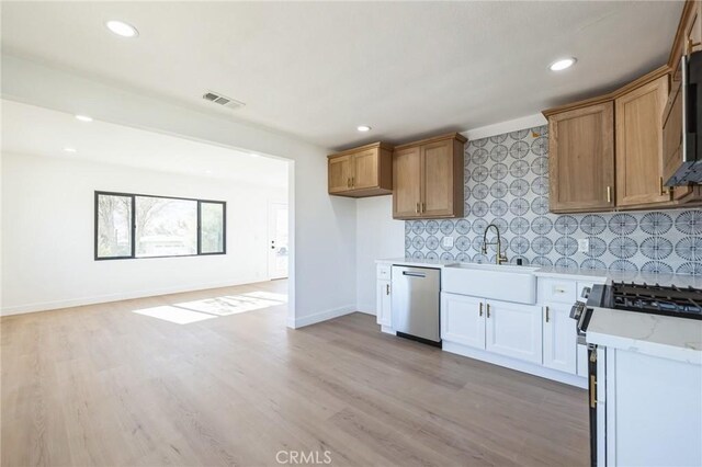 kitchen featuring light wood-type flooring, stainless steel appliances, tasteful backsplash, and sink