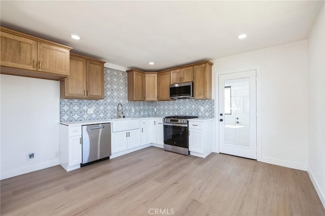 kitchen with appliances with stainless steel finishes, light hardwood / wood-style floors, tasteful backsplash, and sink