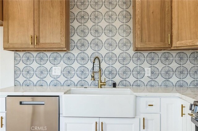 interior space featuring light stone counters, sink, white cabinetry, and tasteful backsplash