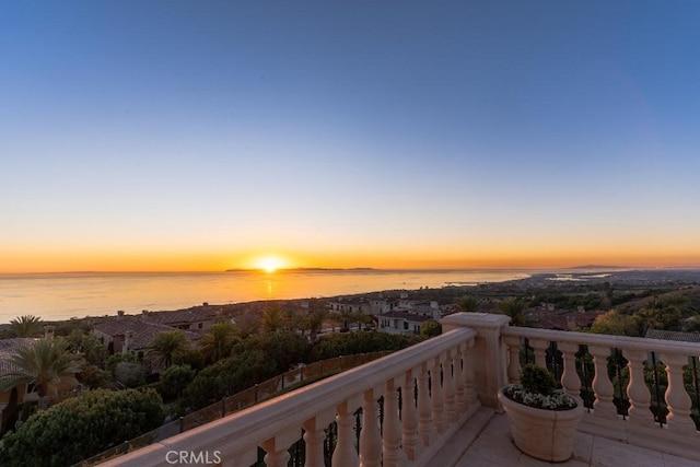 balcony at dusk featuring a water view