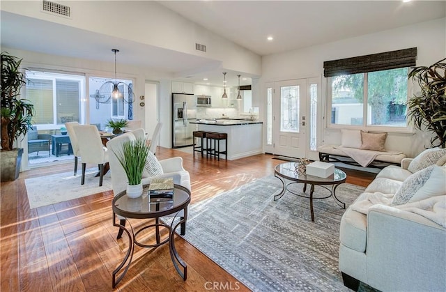 living room with an inviting chandelier, lofted ceiling, and wood-type flooring