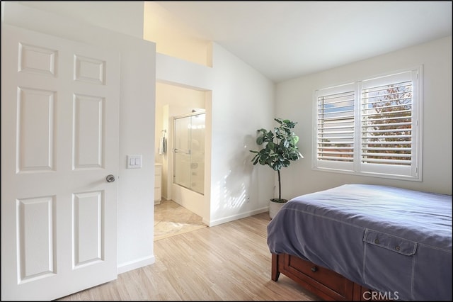 bedroom with connected bathroom, lofted ceiling, and light wood-type flooring