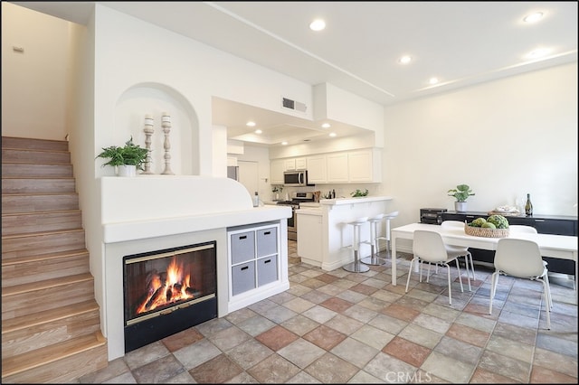 kitchen featuring white cabinetry, appliances with stainless steel finishes, a center island, and a breakfast bar area