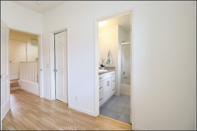 interior space with vanity, combined bath / shower with glass door, and wood-type flooring