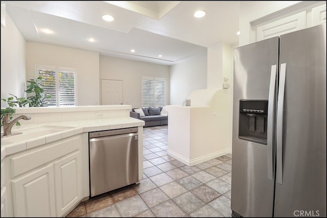 kitchen with sink, tile counters, white cabinets, and stainless steel appliances