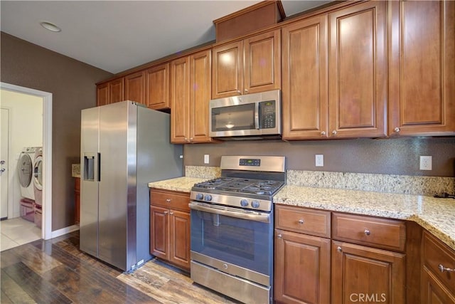 kitchen featuring light stone counters, stainless steel appliances, dark hardwood / wood-style floors, and washer and clothes dryer