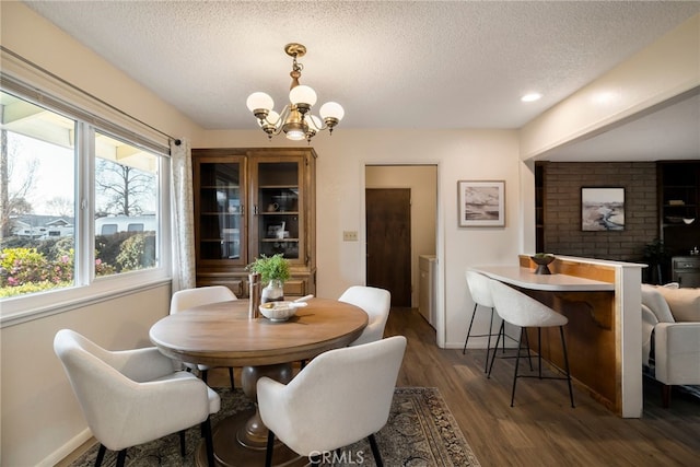 dining room featuring a textured ceiling, dark hardwood / wood-style flooring, and a notable chandelier